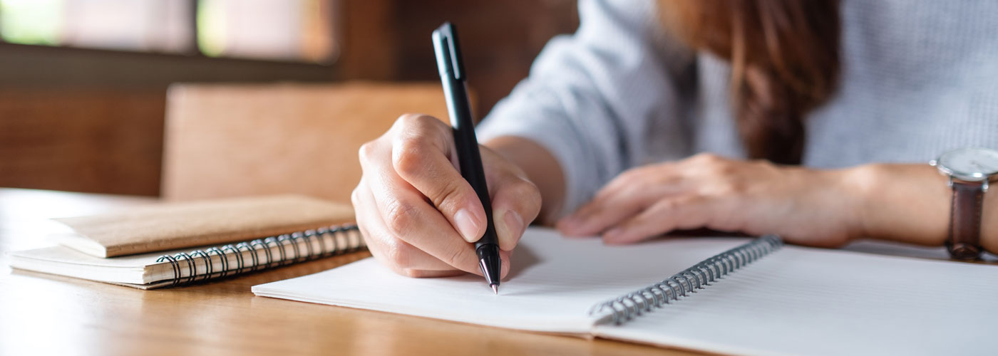 closeup-image-of-a-woman-writing-on-a-blank-notebook